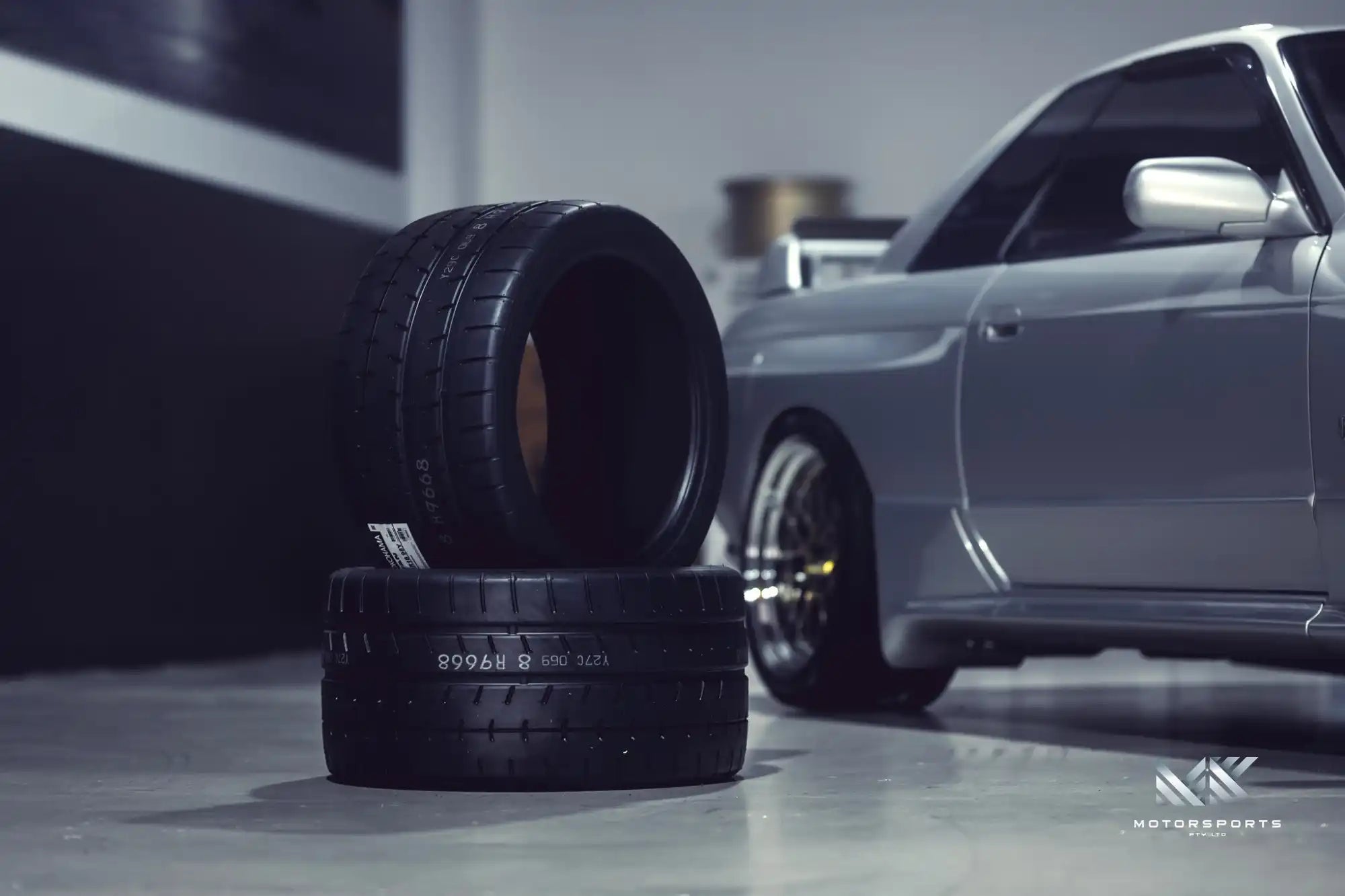 Two stacked, high-performance car tires with distinct tread patterns.