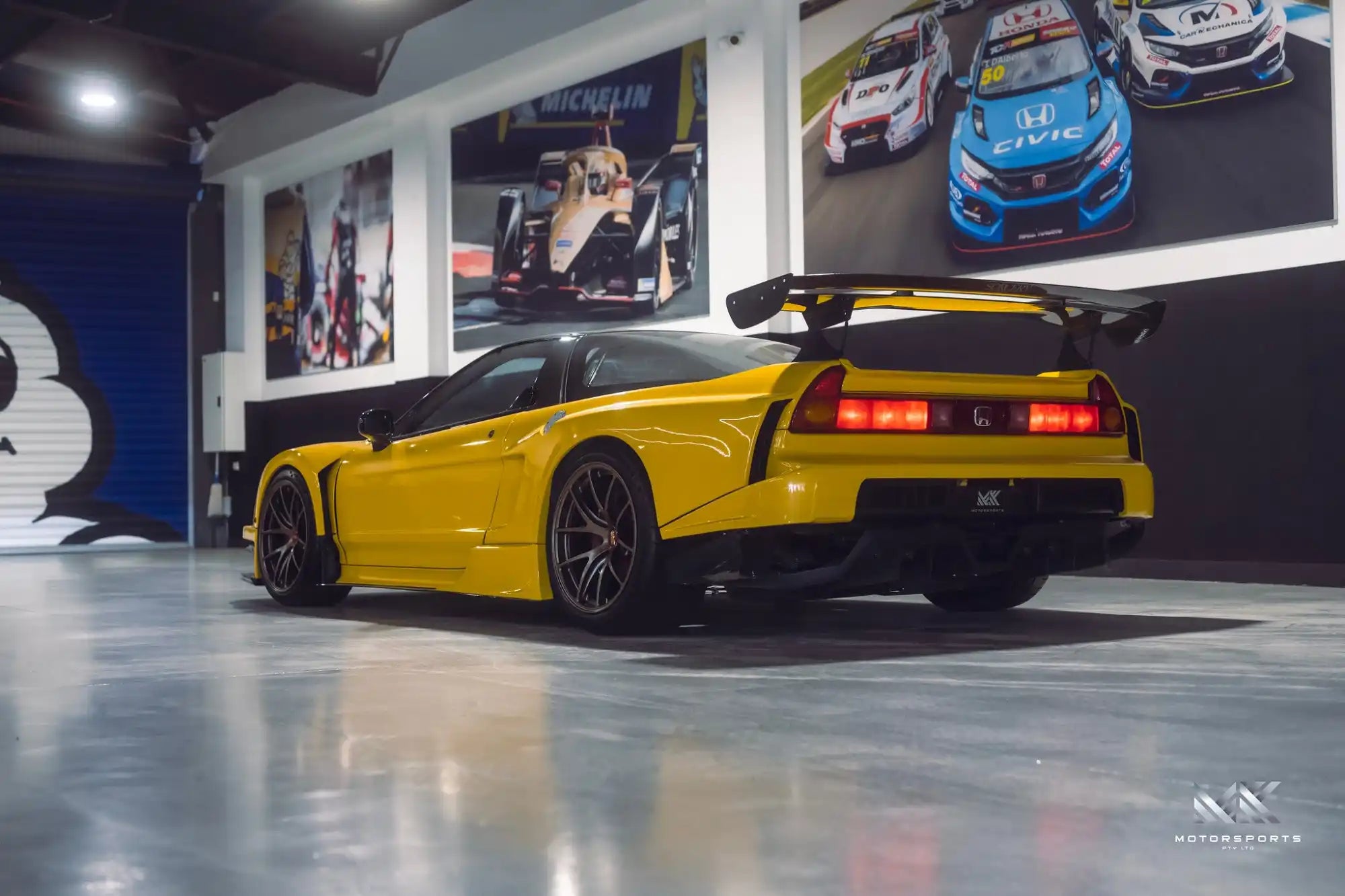 A bright yellow Honda NSX sports car with a large rear wing.