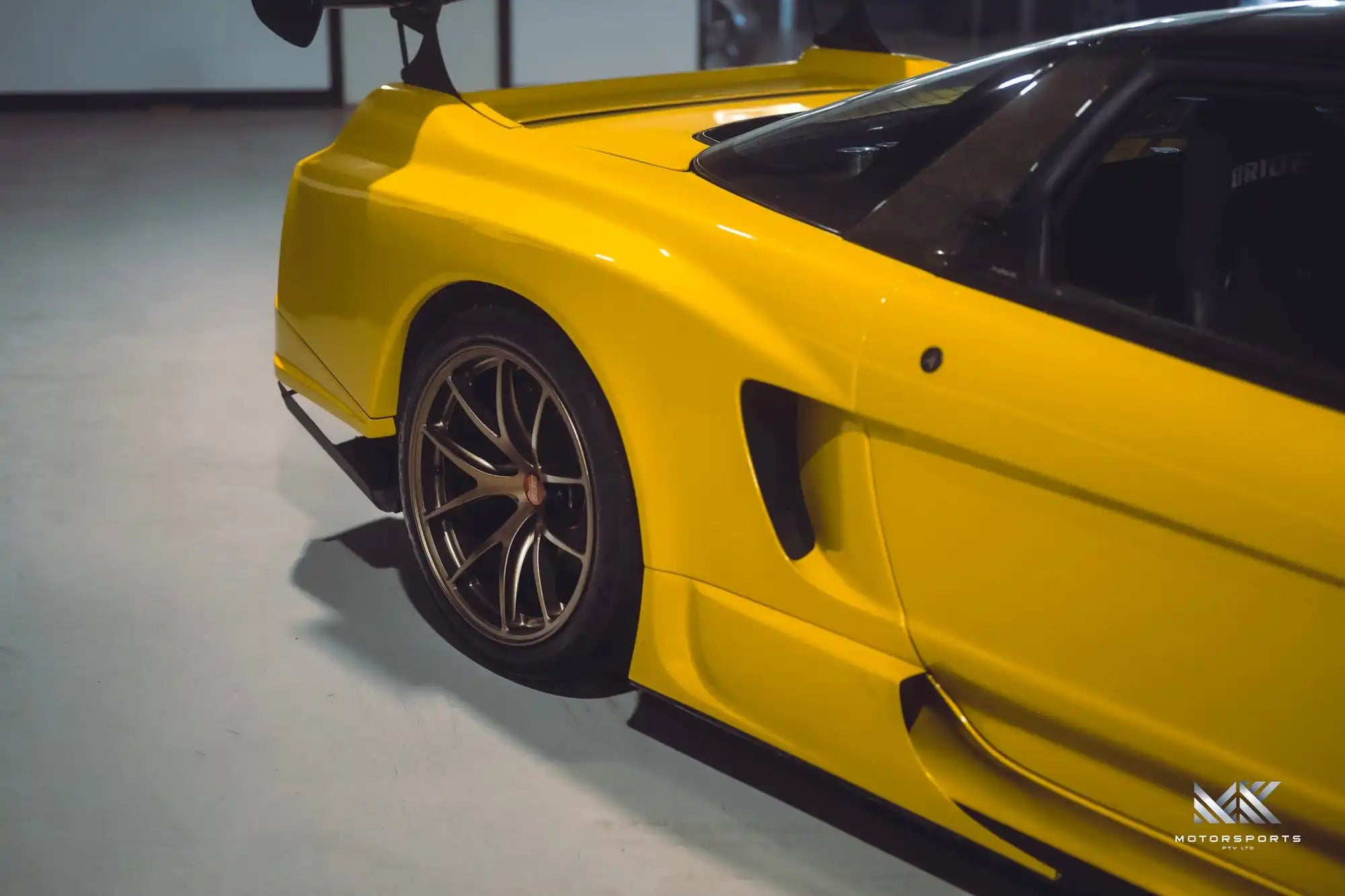 Bright yellow sports car with a large rear spoiler and custom wheels.
