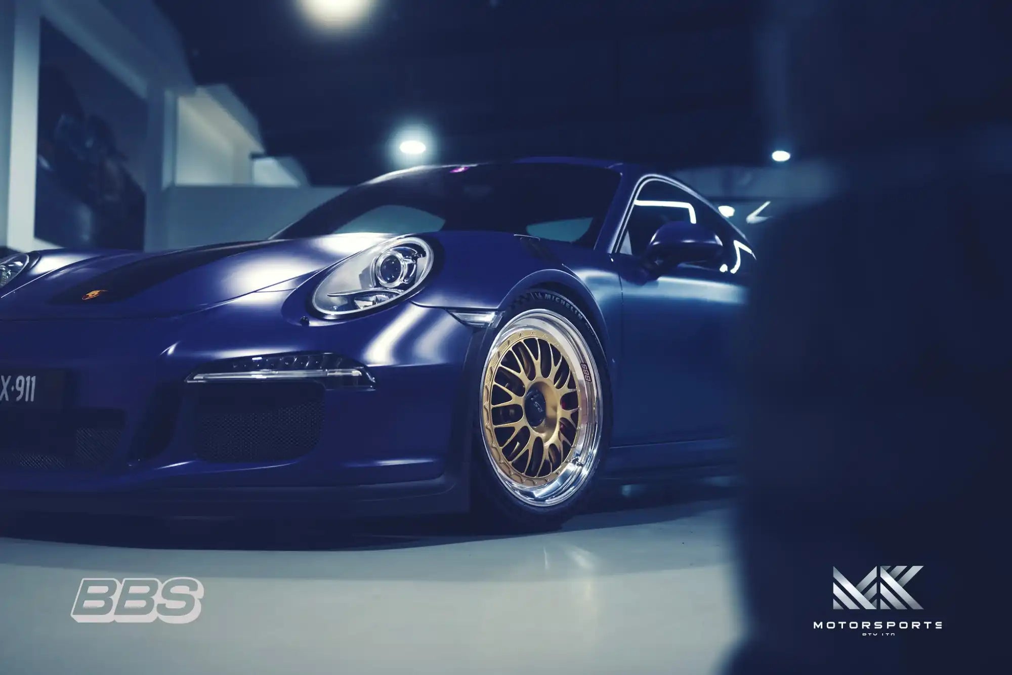 A dark blue Porsche 911 with gold BBS wheels.