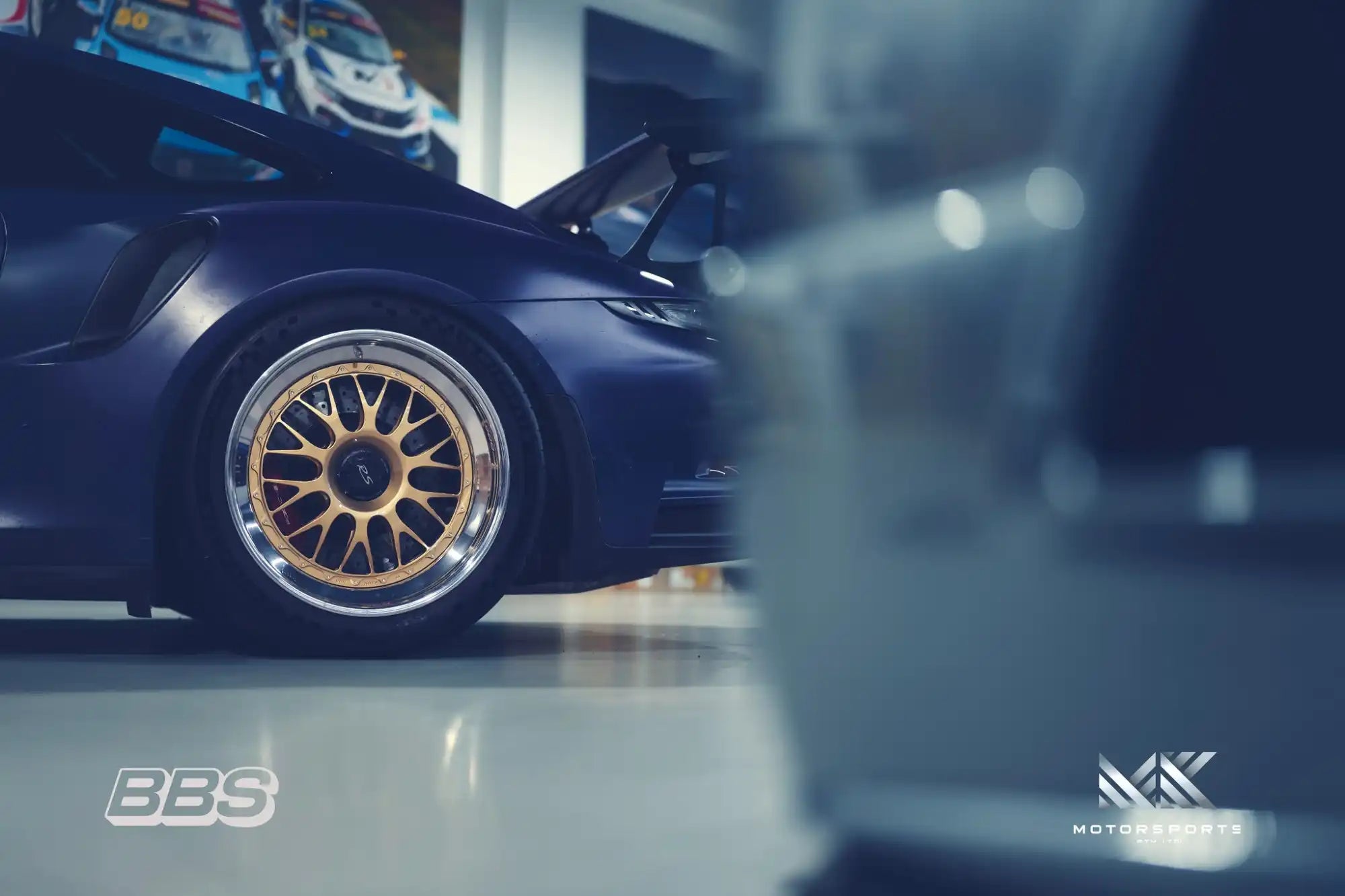 A dark blue Porsche with gold multi-spoke wheels.