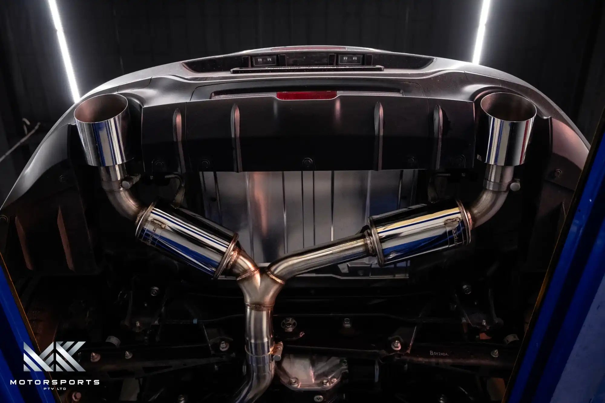 A polished, stainless steel aftermarket exhaust system with dual mufflers and large, round tips.