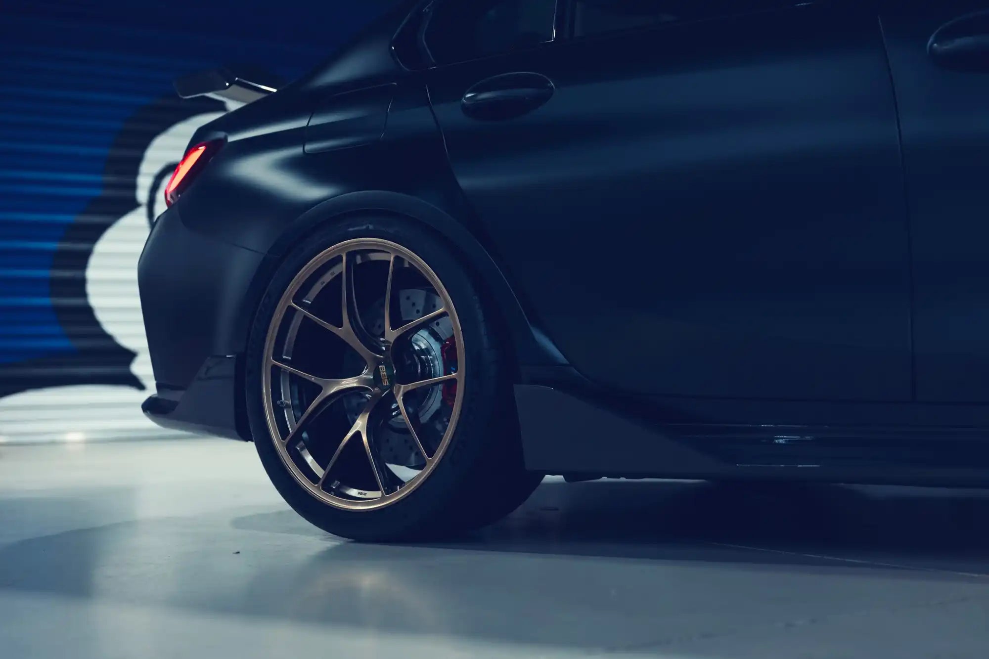 A sleek, dark-colored sports sedan with custom bronze multi-spoke wheels and performance brakes.